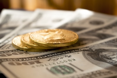 three round gold-colored coins on 100 US dollar banknotes