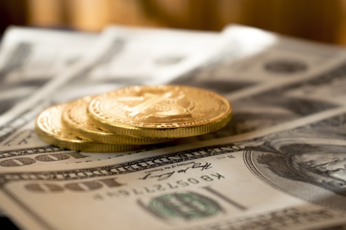 three round gold-colored coins on 100 US dollar banknotes