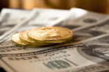 three round gold-colored coins on 100 US dollar banknotes