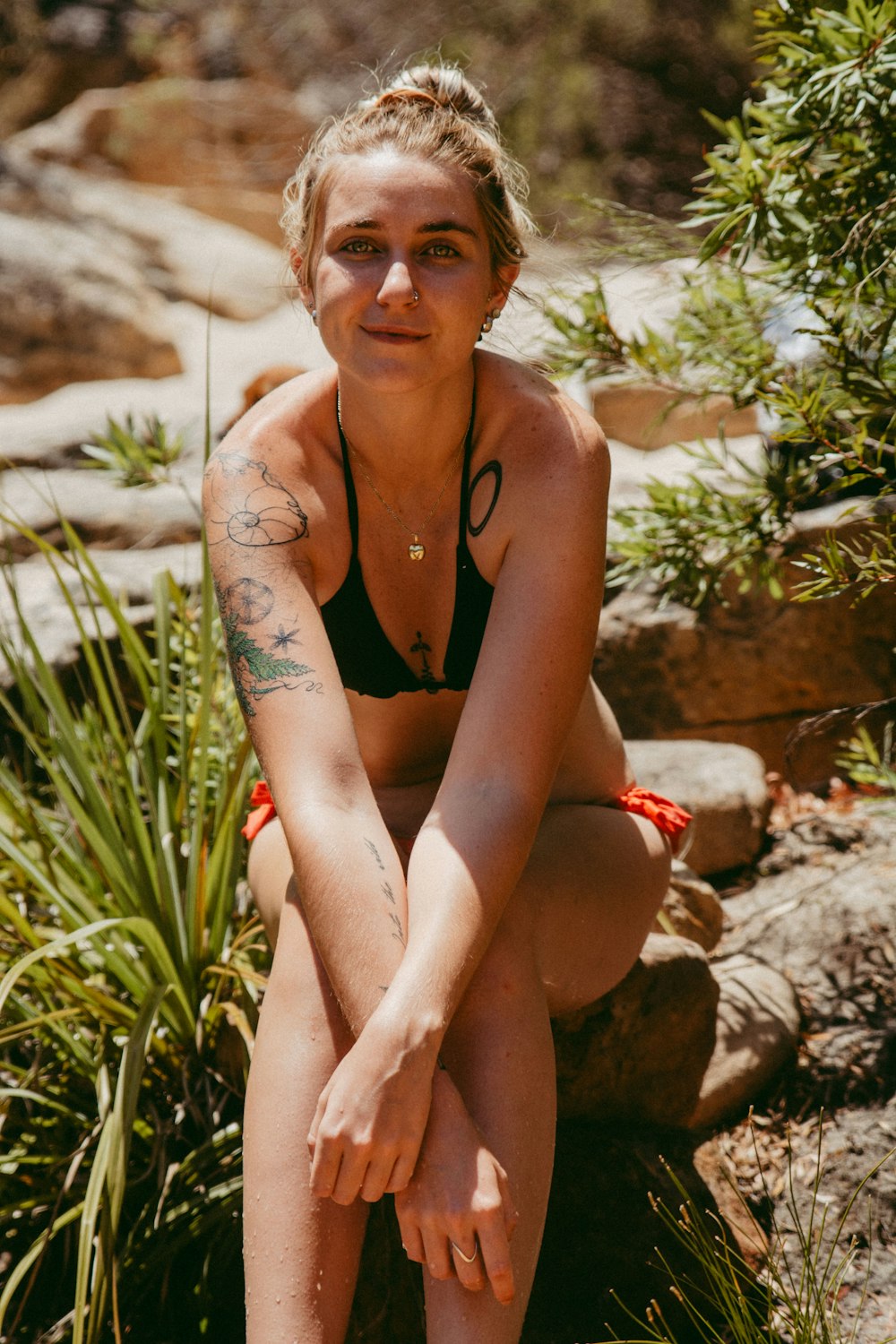 woman wearing black bikini sitting near green plant