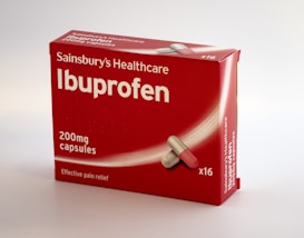 A red box of Sainsbury's Healthcare Ibuprofen is displayed, featuring large white lettering indicating 'Ibuprofen' and '200mg capsules' along with an illustration of a capsule. The label also mentions 'Effective pain relief' and the box contains 16 capsules.