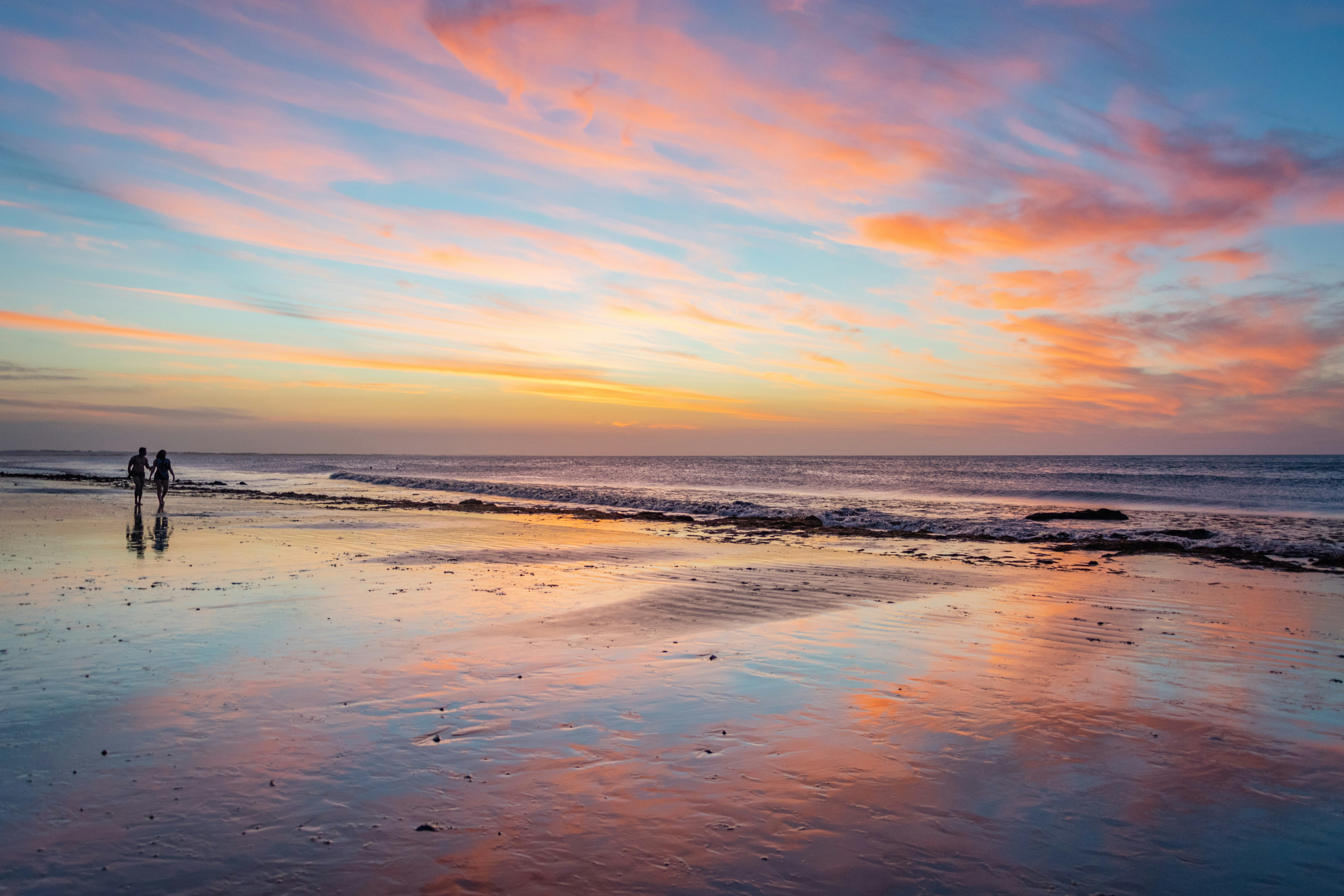 two person walking on shore during golden hour