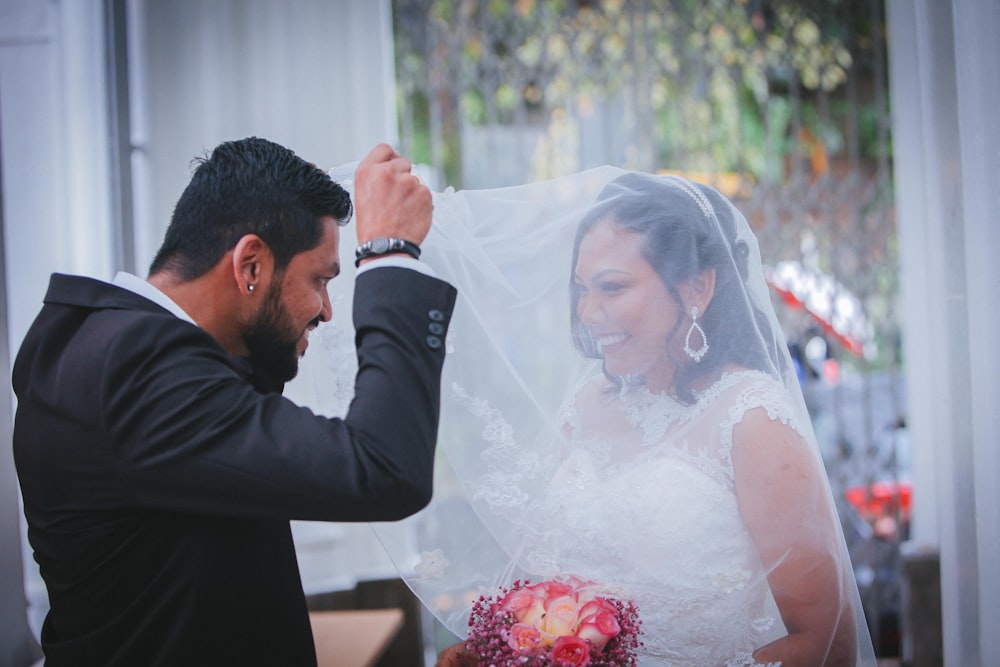 man holding bride's veil on smiling bride
