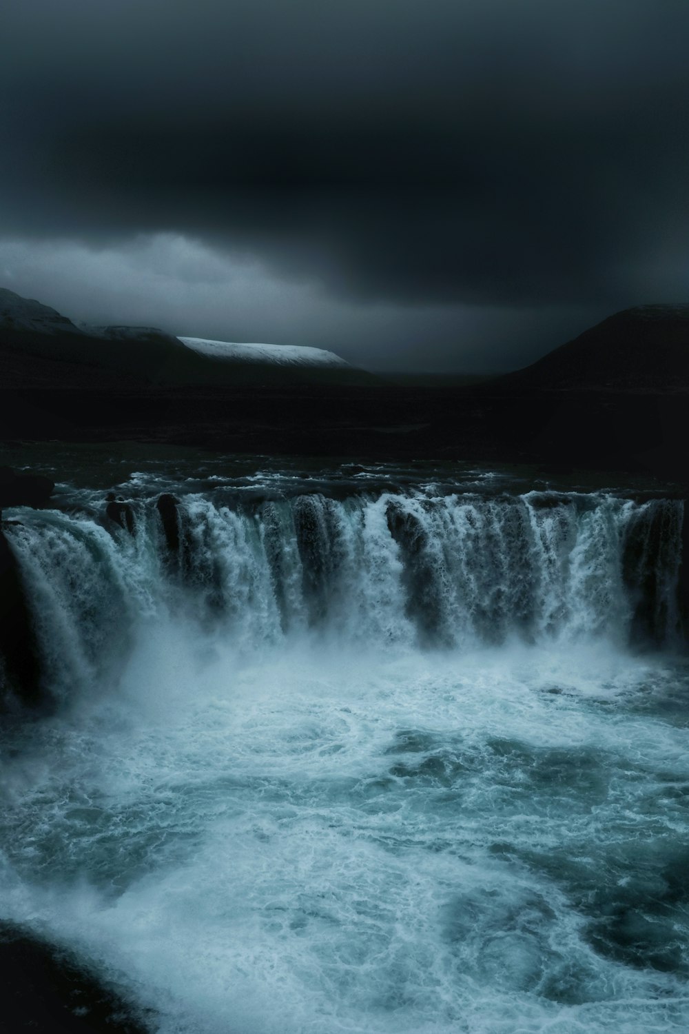 running waterfalls under grey clouds