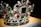 A luxurious crown adorned with an array of precious gemstones and pearls. The design features large red and green stones surrounded by a multitude of smaller clear crystals, creating an intricate and opulent pattern.