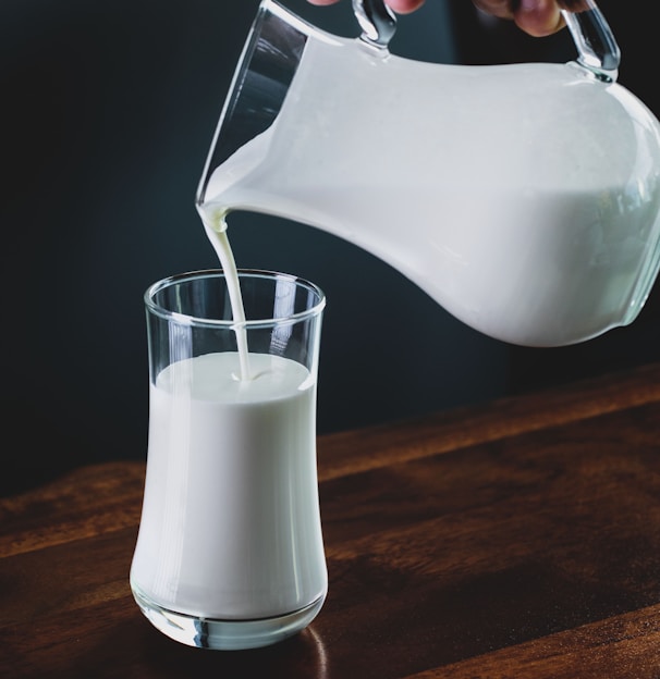 person pours milk into glass