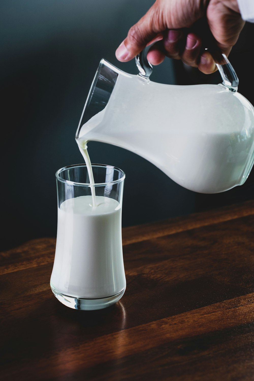 Person gießt Milch in Glas