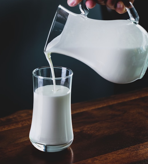 person pours milk into glass