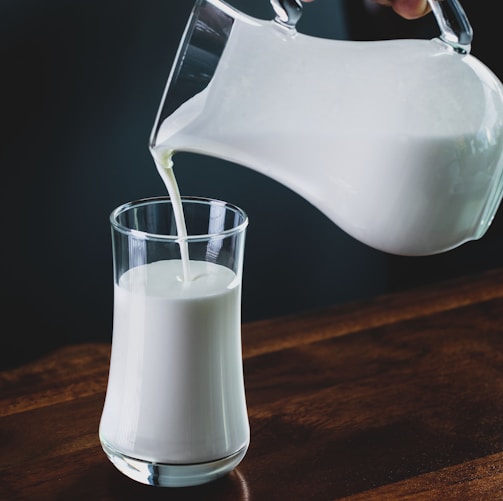 person pours milk into glass