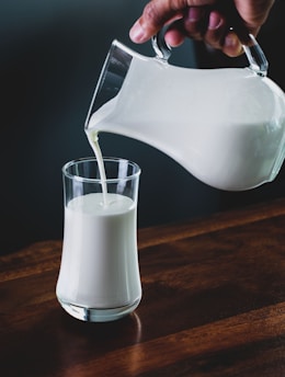 person pours milk into glass