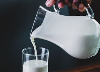 person pours milk into glass