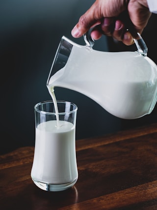 person pours milk into glass