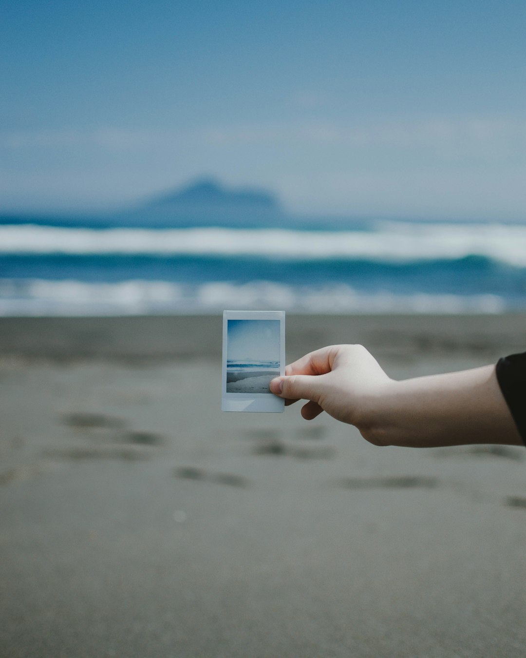 person holds photo of ocean at the beach