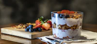 Layered berry yoghurt parfait with granola in a glass jar