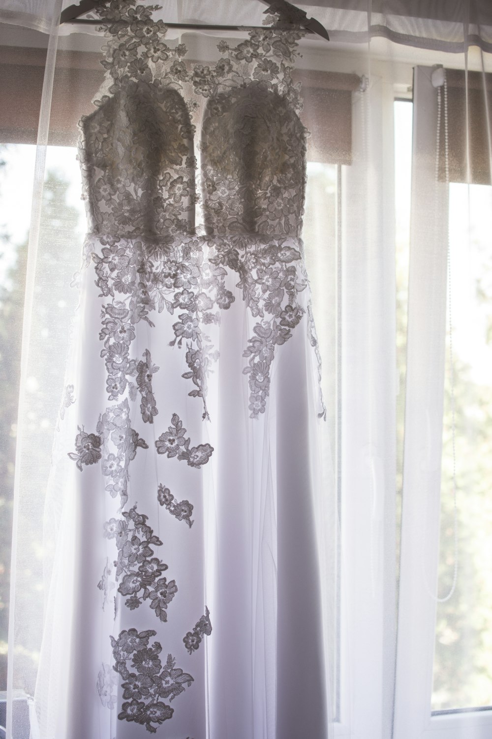 white floral wedding dress hanged near window