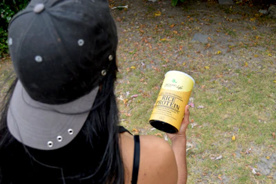 Athlete holding a Trivita protein shake after an intense workout outdoors.