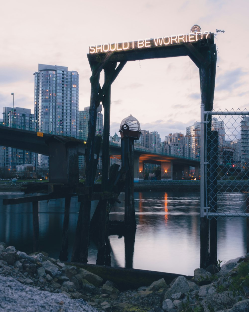 lighted "should be worried?" signage near bridge over body of water