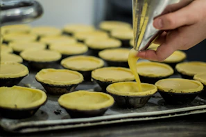 A chef’s hands delicately placing finishing touches on a tray of mini tarts.