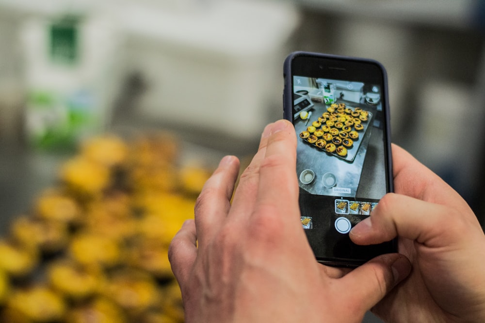 person taking photo of cupcakes