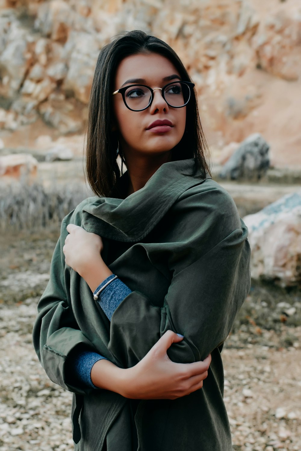 woman wearing eyeglasses standing near brown rock