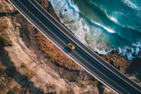 Dynamic image of the Jaecoo J7 cruising along a coastal highway with waves crashing nearby.