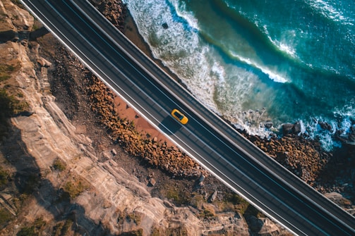 Action shot of a car speeding along a coastal highway.