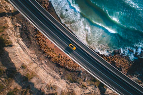 Dynamic image of the Jaecoo J7 cruising along a coastal highway with waves crashing nearby.