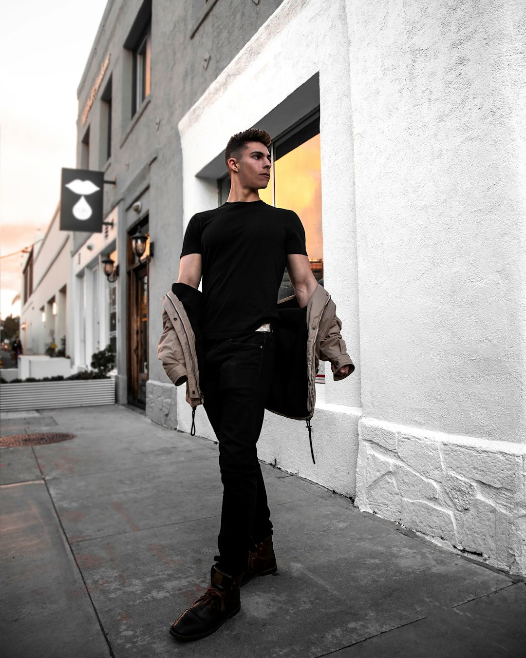 man in black shirt and gray pants leaning on wall