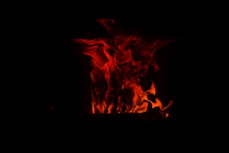 A glowing stylized flame surrounded by sacred geometric patterns in warm golden and red tones.