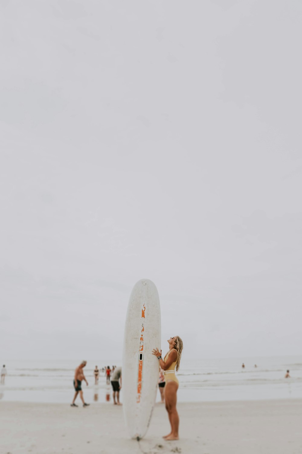 woman standing and holding surfboard near seashore