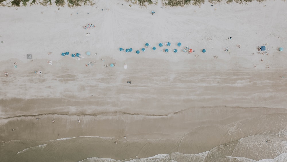 an aerial view of a sandy beach with blue umbrellas