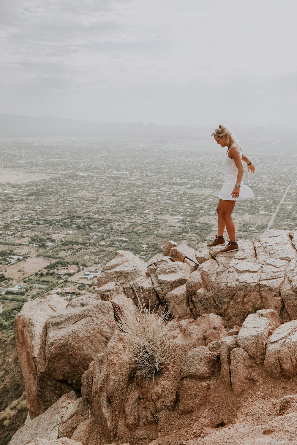 woman wearing white dress standing on brown cliff