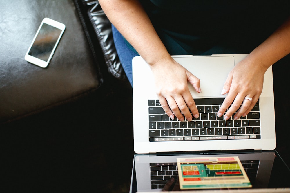 person using MacBook while sitting on chair