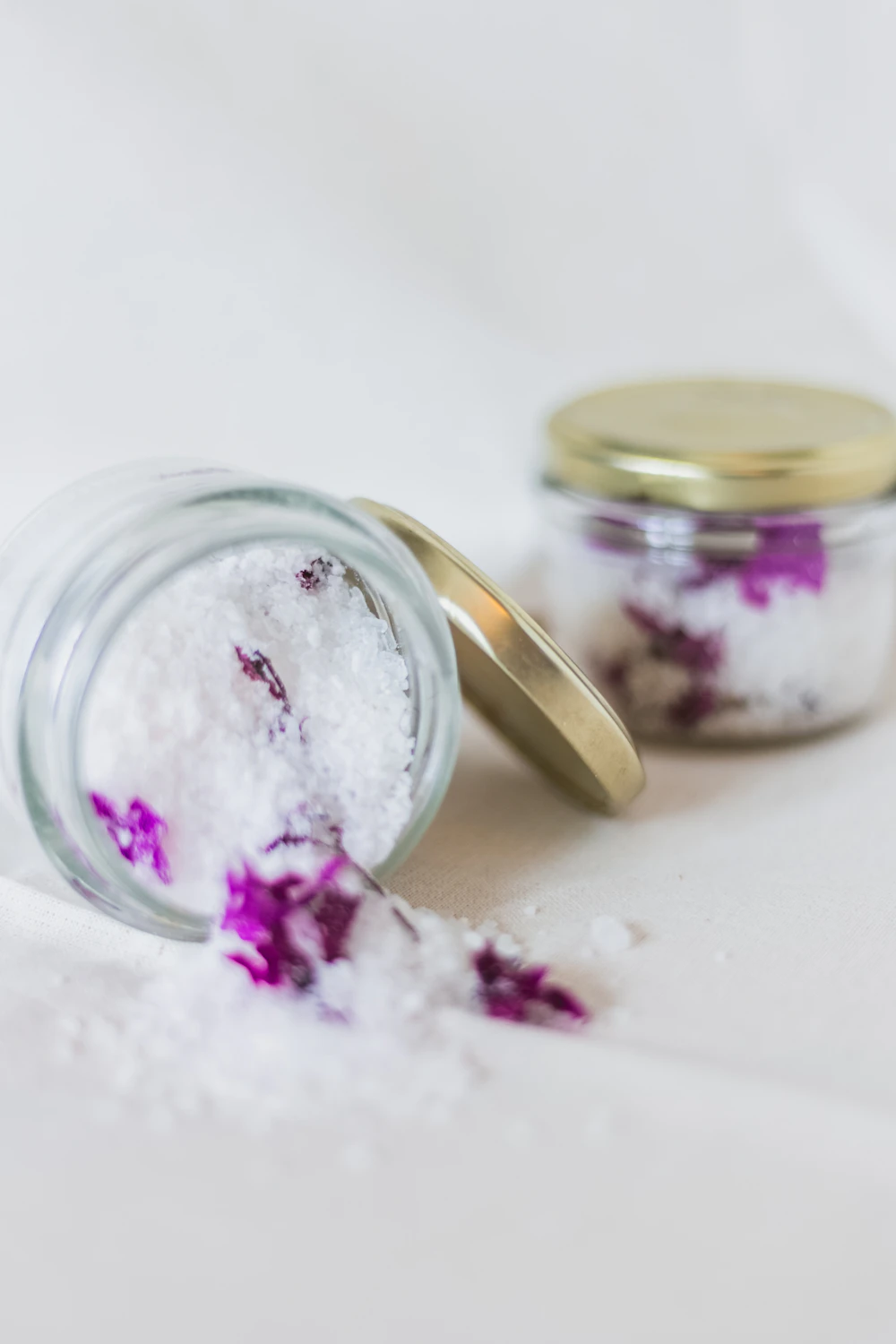 Glass jars of bath salt with purple flower petals