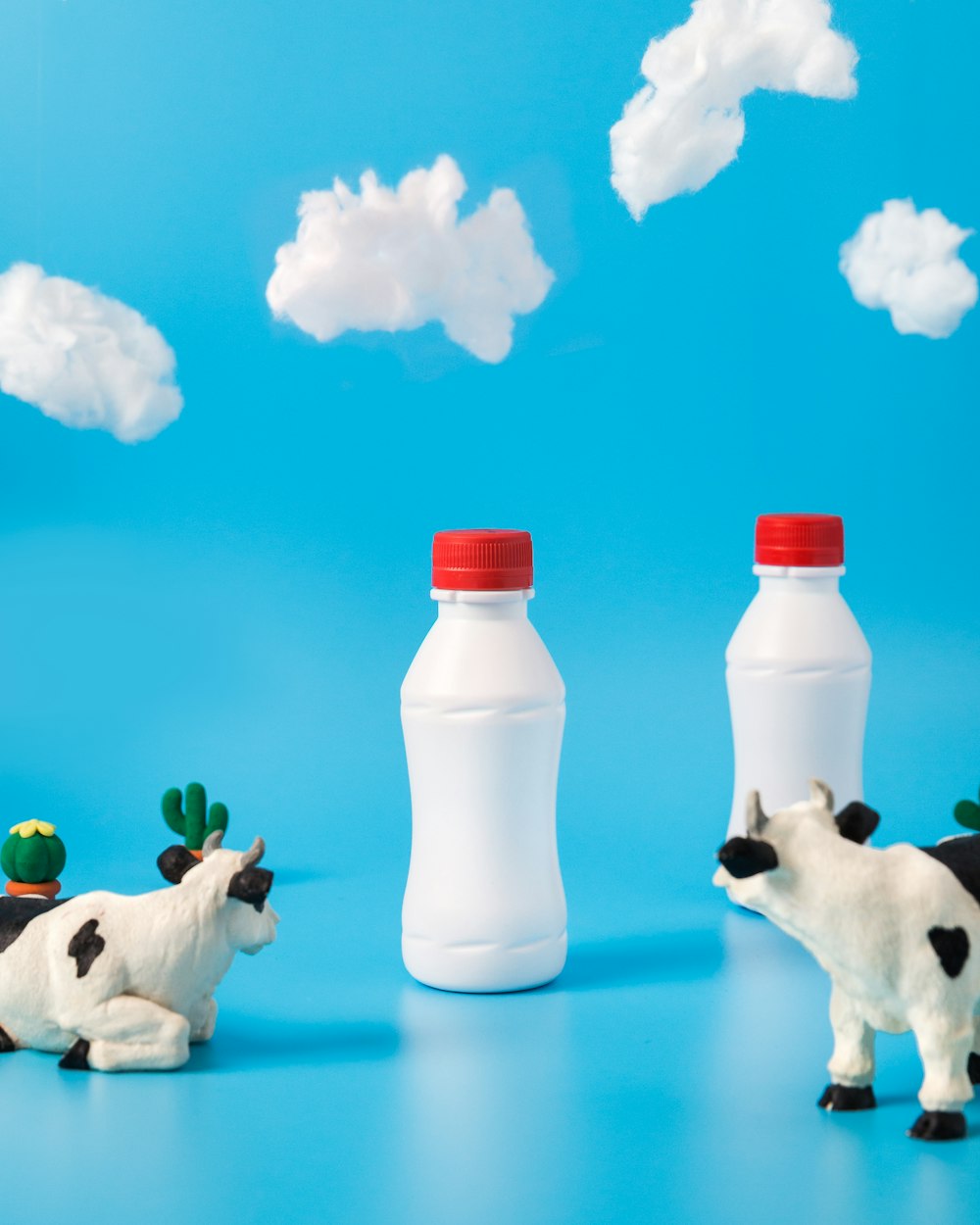 Dos vacas lecheras blancas y negras mirando botellas blancas
