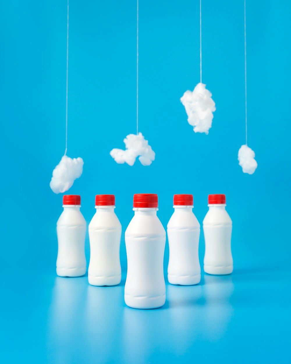 Cinq bouteilles en plastique blanc sur une surface bleue