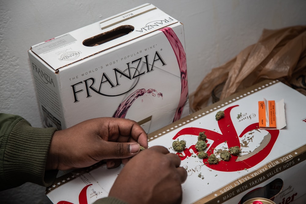 person holding kush on top of box