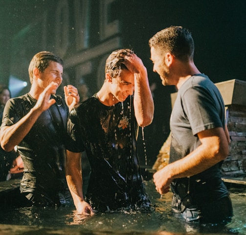 three men standing on black tub full of water