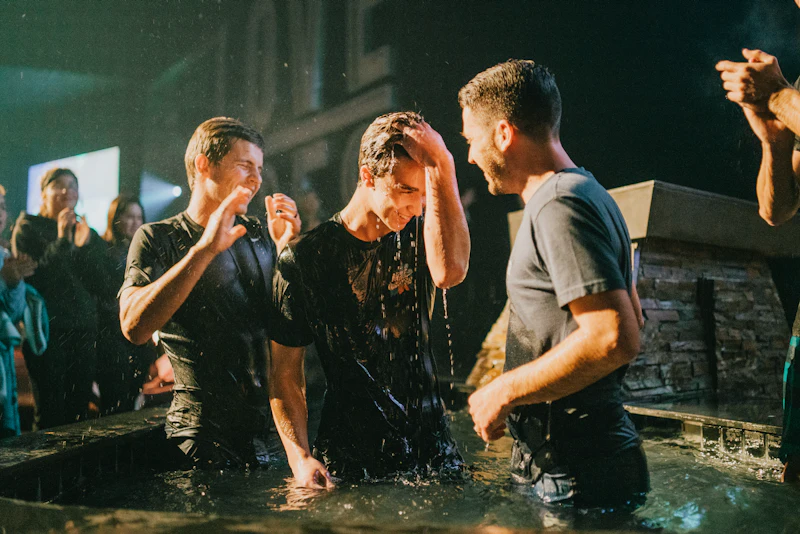 A woman standing in water with her arms raised after being baptised