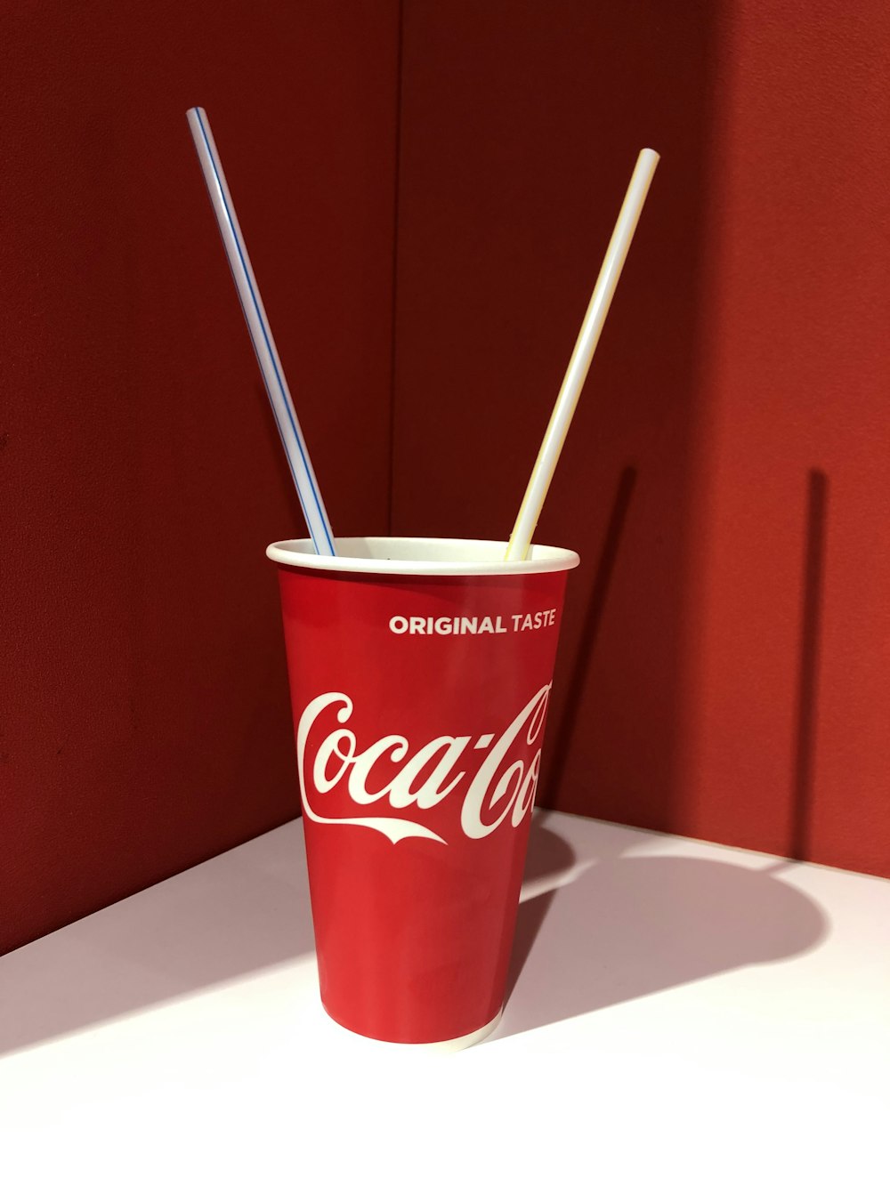 Vaso desechable de Coca-Cola encima de la mesa blanca