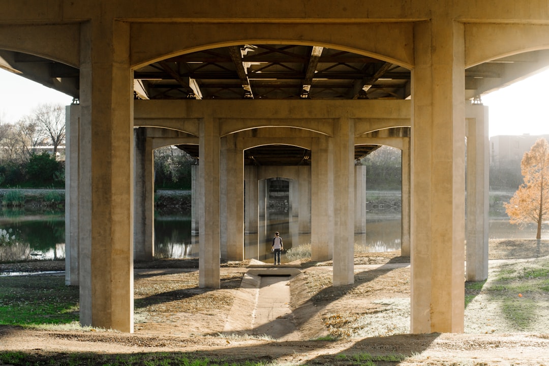 selective focus photography of person standing under bridge during daytime