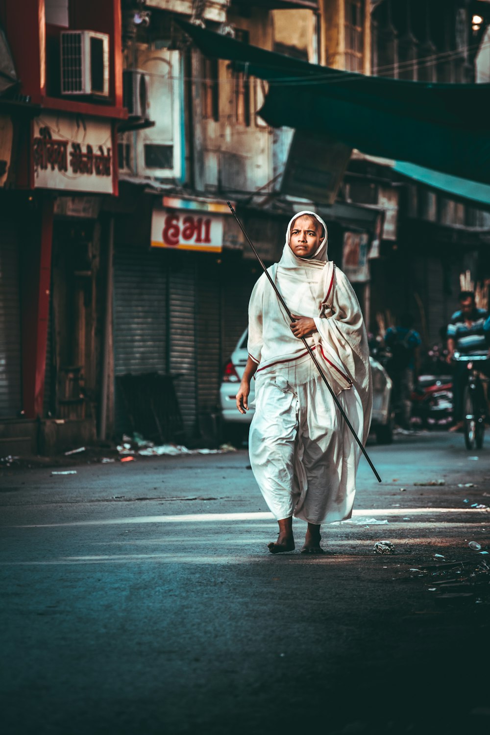 person walking on street while holding stick during daytime