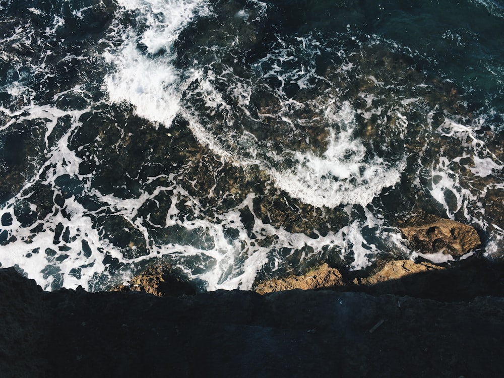 photo of ocean waves and shoreline with brown boulder rocks