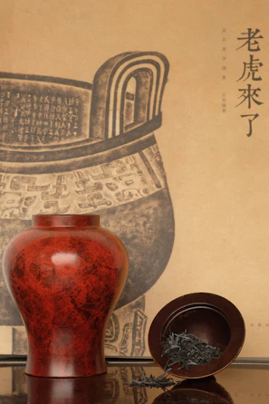 A vibrant red ceramic vase catching sunlight on a wooden shelf.