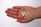 A hand is holding three capsules that are half blue and half white, set against a plain white background. The person is wearing a silver ring on the ring finger.