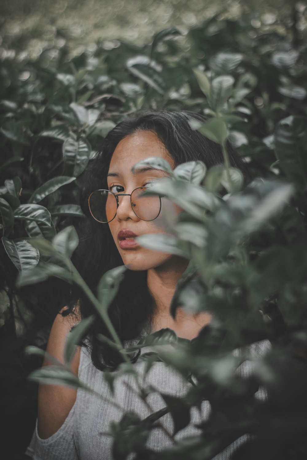 woman standing behind bushes