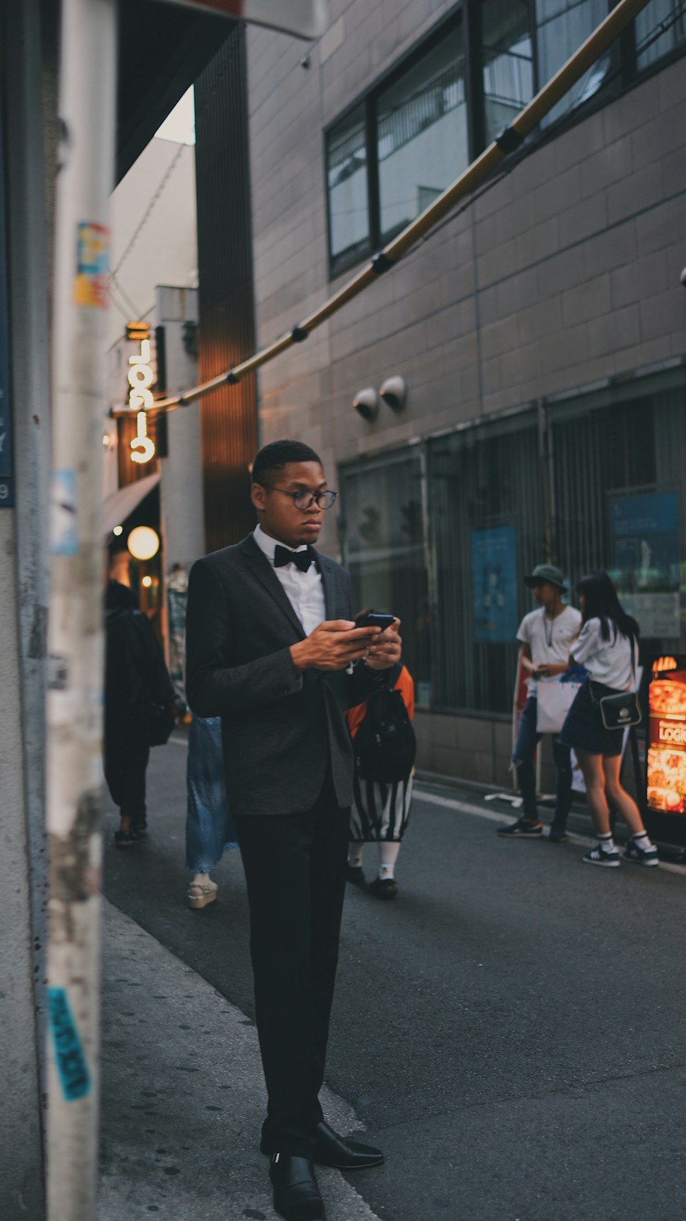 man holding phone standing beside roadway