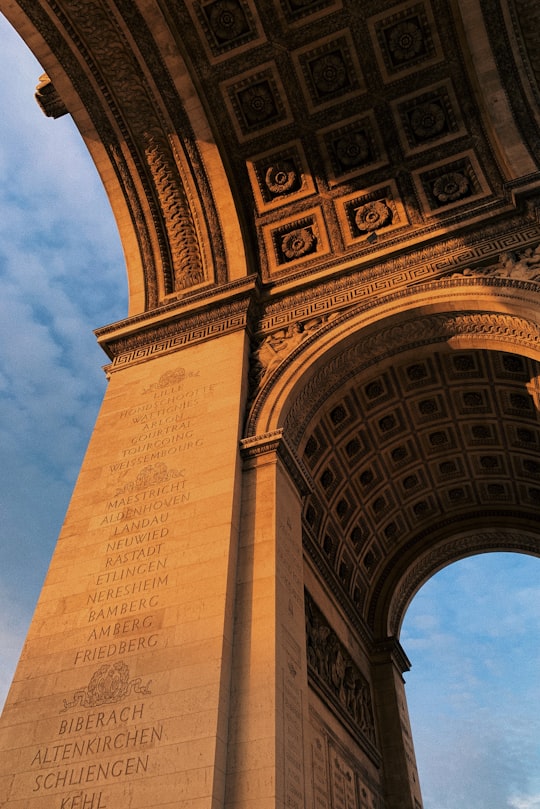 low angle photography of brown concrete building under blue sky during daytime in Arc de Triomphe France