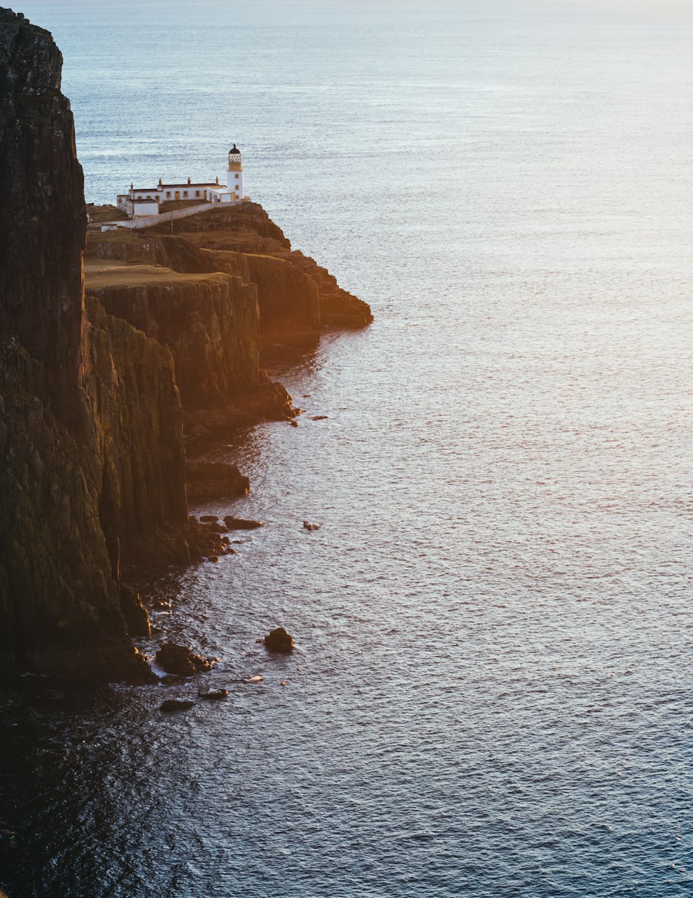 white lighthouse on hill near body of water