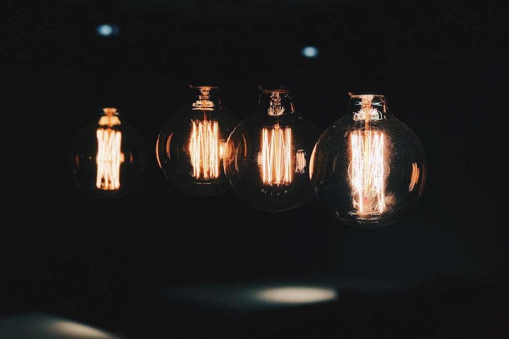 vier beleuchtete Edison-Glühbirnen im Dunkeln